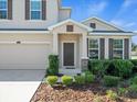 Welcoming front entrance with neat landscaping, neutral stucco and charming brown shutters at 13366 Barkingside Pl, Spring Hill, FL 34609