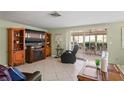 Cozy living room with tile floors, an entertainment center, and a sliding glass door to the screened in patio at 15635 Bertram Dr, Hudson, FL 34667