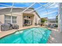 Screened-in pool area with patio furniture, lounge chairs, and a pristine, sparkling swimming pool at 1905 Firefern Ct, Trinity, FL 34655