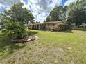 Landscaped front yard with mature tree, showcasing the exterior of this inviting single-story home at 5406 Dartmouth Rd, New Port Richey, FL 34652