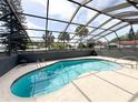 Enclosed backyard pool featuring clear blue water, a screened enclosure, and a spacious surrounding patio at 7026 Whitethorn Ct, Port Richey, FL 34668