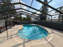 Enclosed backyard pool featuring clear blue water, a screened enclosure, and a spacious surrounding patio at 7026 Whitethorn Ct, Port Richey, FL 34668