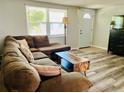 Bright living room featuring a comfortable sectional sofa, wood-look floors, and lots of natural light at 9136 Mark Twain Ln, Port Richey, FL 34668