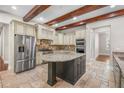 Gourmet kitchen featuring an island, stone floors, stainless steel appliances, and wooden beams at 10110 Weeks Dr, Brooksville, FL 34601