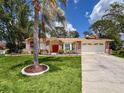 Charming one-story home with a bright red front door, mature landscaping, and an expansive driveway at 1280 Thornton Ct, Spring Hill, FL 34608