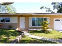 Close up front exterior featuring updated windows, neutral color palette, walkway, and well maintained lawn at 1540 Lime St, Clearwater, FL 33756