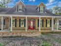 Charming home featuring a welcoming front porch with a red door, and dormer windows at 18308 Valor Path, Brooksville, FL 34604