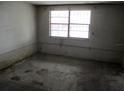 Vacant bedroom with unfinished walls, concrete floor, and barred window at 4520 Iris Dr, New Port Richey, FL 34652