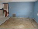 Empty living room with blue walls, worn carpet, and an adjacent room with wall damage at 4520 Iris Dr, New Port Richey, FL 34652