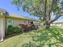 Exterior of the home featuring mature trees, well-maintained lawn, several large windows, and manicured landscaping at 4836 Alamo Ct, New Port Richey, FL 34655