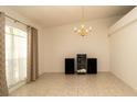 Empty living room with tiled floors, vaulted ceiling, large window, and chandelier lighting at 5092 Roble Ave, Spring Hill, FL 34608