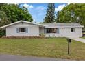 Single-story home with a well-kept lawn and mature trees under a beautiful blue sky, creating a serene setting at 6335 Kings Ct, New Port Richey, FL 34653