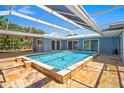 Inviting in-ground pool within a screened enclosure, surrounded by a travertine deck and lush landscaping at 7230 17Th N Ln, St Petersburg, FL 33702