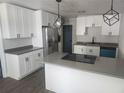 Modern kitchen with white cabinets, stainless steel appliances, gray countertops, and contemporary lighting at 825 Lincoln Ave, Tarpon Springs, FL 34689