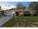 Attractive single-story home with a well-manicured lawn, stone accents, and an attached two-car garage at 8466 Eldridge Rd, Spring Hill, FL 34608