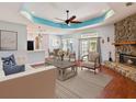 Inviting living room featuring a stone fireplace, tray ceiling, and neutral decor, offering a cozy and stylish space at 10318 Piper Dr, New Port Richey, FL 34654