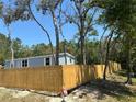 Light blue home with white trim surrounded by a newly installed wooden fence at 11444 Lake Dr, New Port Richey, FL 34654