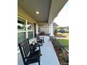 Inviting front porch with rocking chairs, decorative columns, and stone accents at 12848 Hilary St, Spring Hill, FL 34609