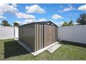 Backyard featuring a metal storage shed surrounded by a well-maintained lawn and white fencing at 12848 Hilary St, Spring Hill, FL 34609