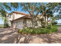 Charming home featuring a brick driveway, a three-car garage and mature trees surrounding the property at 1473 Sail Harbor Cir, Tarpon Springs, FL 34689