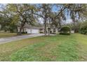 Spacious home with a three-car garage, mature trees, and a well-manicured lawn at 18328 Treehaven Dr, Hudson, FL 34667