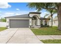 Charming single-story home featuring a manicured lawn, arched entry, and a spacious two-car garage at 18456 Merseyside Loop, Land O Lakes, FL 34638