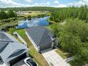Beautiful single-story home with a well-manicured lawn, long driveway, and a view of a serene pond at 18456 Merseyside Loop, Land O Lakes, FL 34638