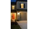 Exterior shot of a townhome featuring a red front door and a one-car garage at night at 31718 Blue Passing Loop, Wesley Chapel, FL 33545