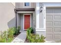 Inviting front entrance with a bright red door, well-manicured bushes, and a sidelight at 31718 Blue Passing Loop, Wesley Chapel, FL 33545