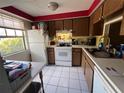 Functional kitchen featuring white appliances, tile flooring, and wood cabinetry at 4223 Sheldon Pl # H, New Port Richey, FL 34652