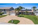 Charming single-story home featuring a brick driveway, two-car garage, and well-manicured lawn with beautiful tropical landscaping at 5033 Cabrilla Ct, New Port Richey, FL 34652