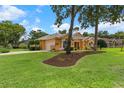 Beautiful exterior showing a manicured lawn, mature trees, and an attached two-car garage at 5110 Championship Cup Ln, Spring Hill, FL 34609