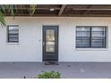 A cozy entrance with a black door and a 'home' welcome mat, flanked by windows on a sunny day at 5640 Ferguson Ct # 2106, New Port Richey, FL 34652