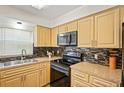 Well-lit kitchen with black appliances, wood cabinetry, and attractive tile backsplash at 6047 Elmhurst Dr # 5A, New Port Richey, FL 34653