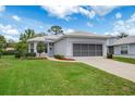 Single-story home featuring a well-manicured lawn and two-car garage at 9147 Rhett Ln, Weeki Wachee, FL 34613