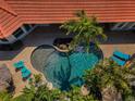 Aerial view of a private pool surrounded by brick pavers, palm trees and comfortable lounge chairs at 10712 Pontofino Cir, Trinity, FL 34655