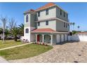 Three-story home with lush landscaping, a paver driveway, and a three-car garage at 13741 Judy Ave, Hudson, FL 34667
