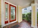 Covered entryway featuring a red-framed glass door and brick flooring with a small welcome mat at 16022 Westerham Dr, Tampa, FL 33647