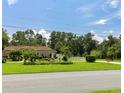 Lovely home exterior featuring lush green lawn, mature trees, and a white picket fence at 22106 Garmisch Way, Brooksville, FL 34601