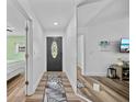 Inviting foyer with sleek hardwood floors, accent rug, and decorative front door, offering a modern aesthetic at 7101 N 18Th St, Tampa, FL 33610