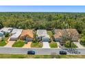 A scenic view of single-story homes nestled in a lush, wooded neighborhood under a bright blue sky at 9398 Mississippi Run, Weeki Wachee, FL 34613