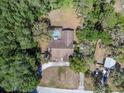 An aerial view of the home features a large lot, mature trees, screened pool and driveway at 10134 Buck Dr, New Port Richey, FL 34654