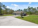 View of home with large driveway, two car garage, and manicured lawn with shrubs at 11730 Hawks Nest Trl, Brooksville, FL 34614