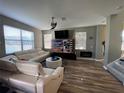 Open living room features wood-look flooring, modern furniture, ceiling fan, and a wall-mounted television at 11796 Crestridge Loop, New Port Richey, FL 34655