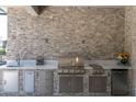 Outdoor kitchen with a built-in grill, sink, and stone backsplash at 12617 Wetmore Ct, Odessa, FL 33556