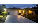 Charming home at dusk, featuring a spacious driveway, two car garage and manicured landscaping at 13100 Fish Cove Dr, Spring Hill, FL 34609