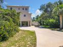 Charming stilt home boasts a circular driveway, boat parking and mature trees, set against a sunny, blue sky at 4514 Fishman Ave, Weeki Wachee, FL 34607