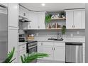 Well-lit kitchen with white cabinets, stainless steel appliances, and stylish decorative elements on the backsplash at 4607 Kennedy Dr, New Port Richey, FL 34652