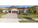 Charming single-story home featuring a tile roof, arched entryway, well-manicured lawn, and spacious three-car garage at 5070 Night Star Trl, Odessa, FL 33556