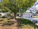 Single-story home boasts a brick facade, spacious driveway, and a well-manicured lawn with a large tree at 6431 Gainsboro Dr, Port Richey, FL 34668